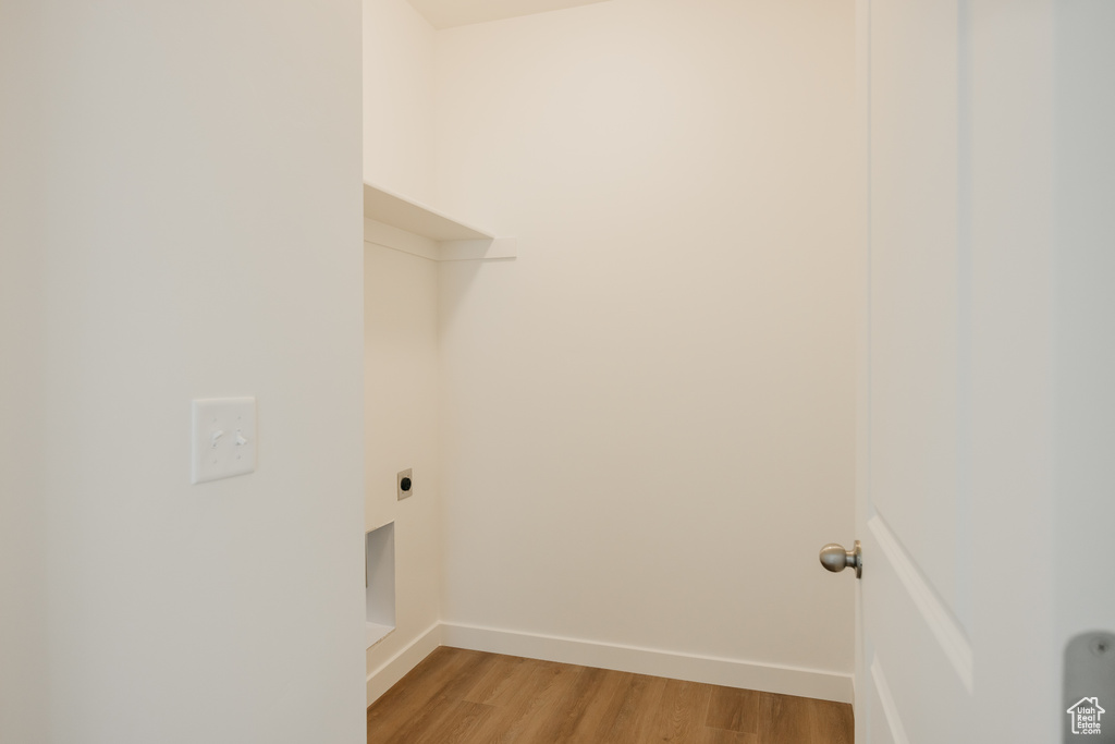 Laundry area with electric dryer hookup, baseboards, and light wood-style floors