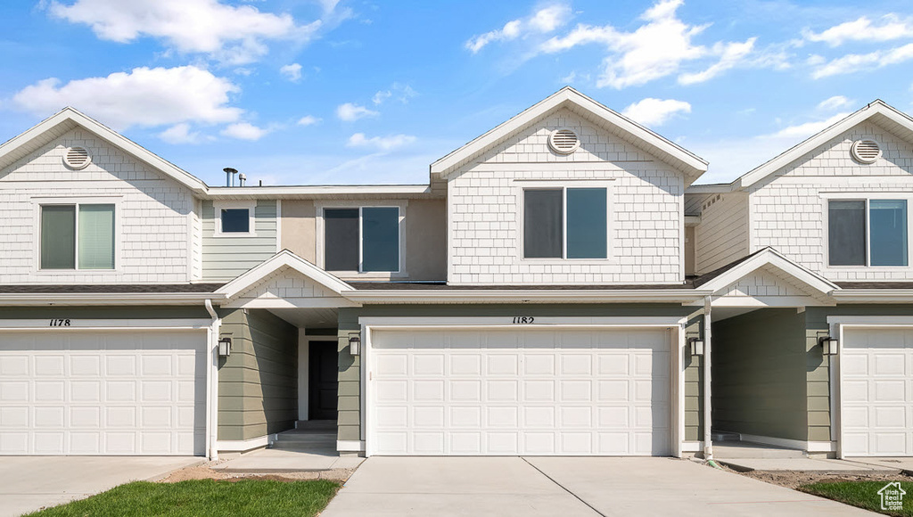 View of property featuring a garage and concrete driveway