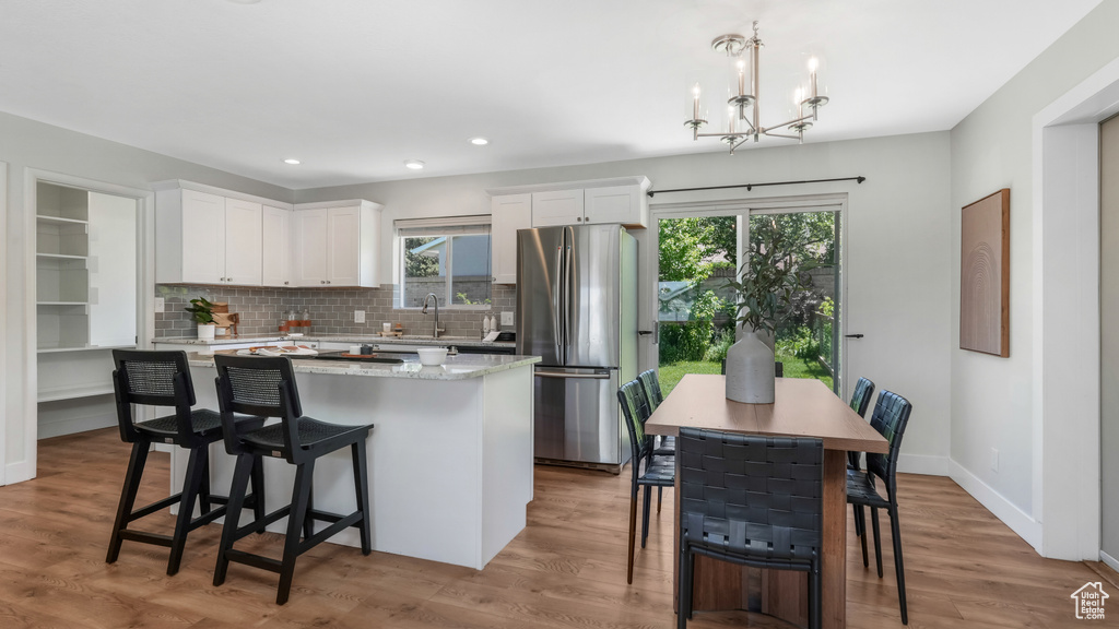 Kitchen featuring freestanding refrigerator, a kitchen island, white cabinets, plenty of natural light, and recessed lighting