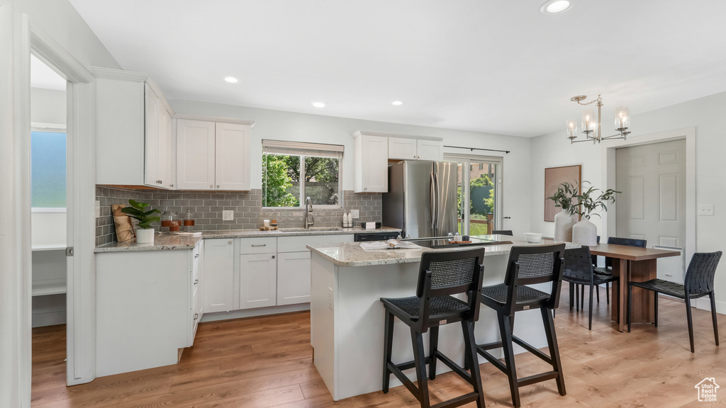 Kitchen with freestanding refrigerator, a sink, white cabinetry, a kitchen island, and recessed lighting