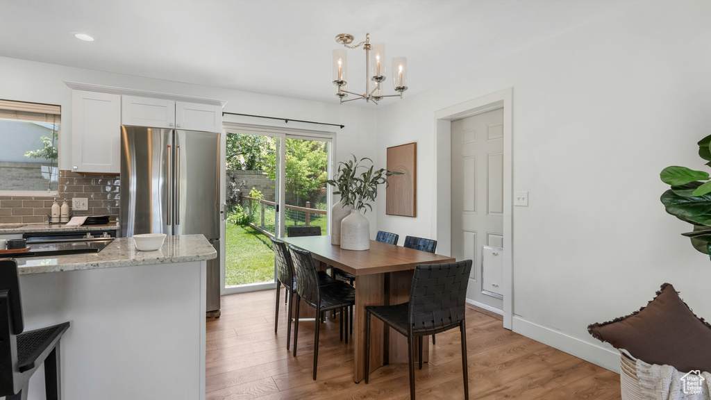 Dining area with a chandelier, light wood-type flooring, baseboards, and recessed lighting