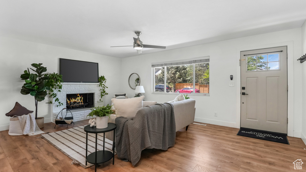 Living area with healthy amount of natural light, a ceiling fan, wood finished floors, and baseboards