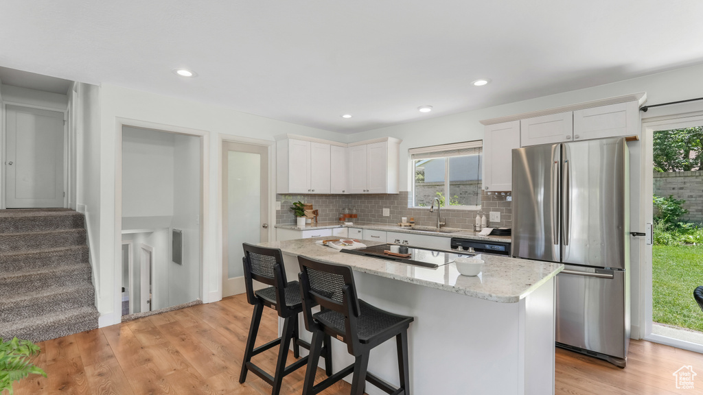 Kitchen featuring freestanding refrigerator, a sink, a center island, healthy amount of natural light, and recessed lighting