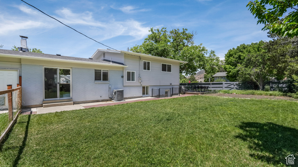 Rear view of house featuring a patio area, central AC, and brick siding