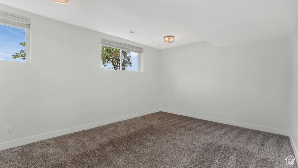 Empty room featuring dark colored carpet and baseboards