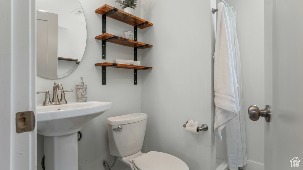 Full bath with toilet, a shower with shower curtain, and baseboards