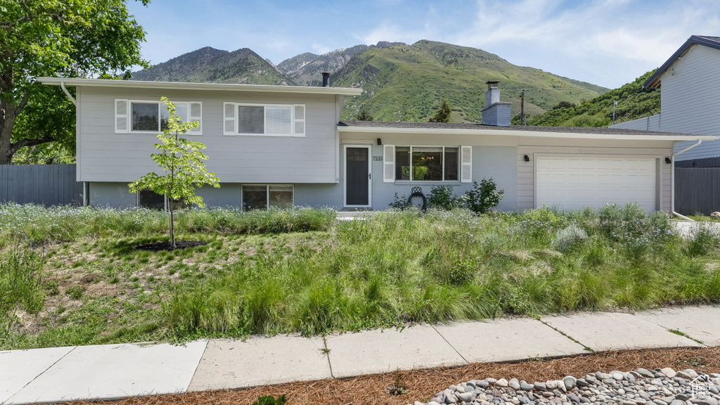 Tri-level home featuring a mountain view, a garage, and a chimney