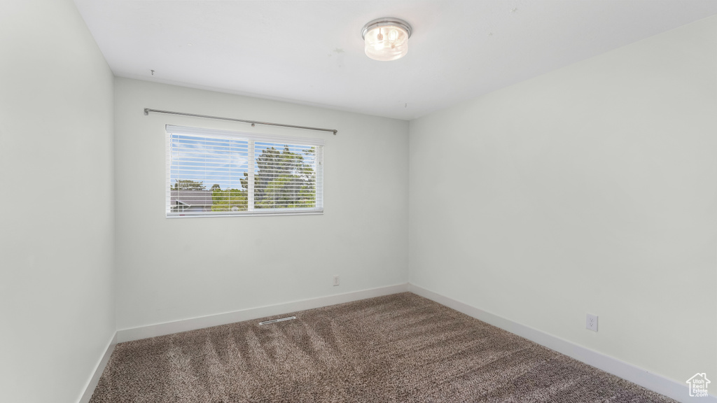Spare room featuring carpet and baseboards