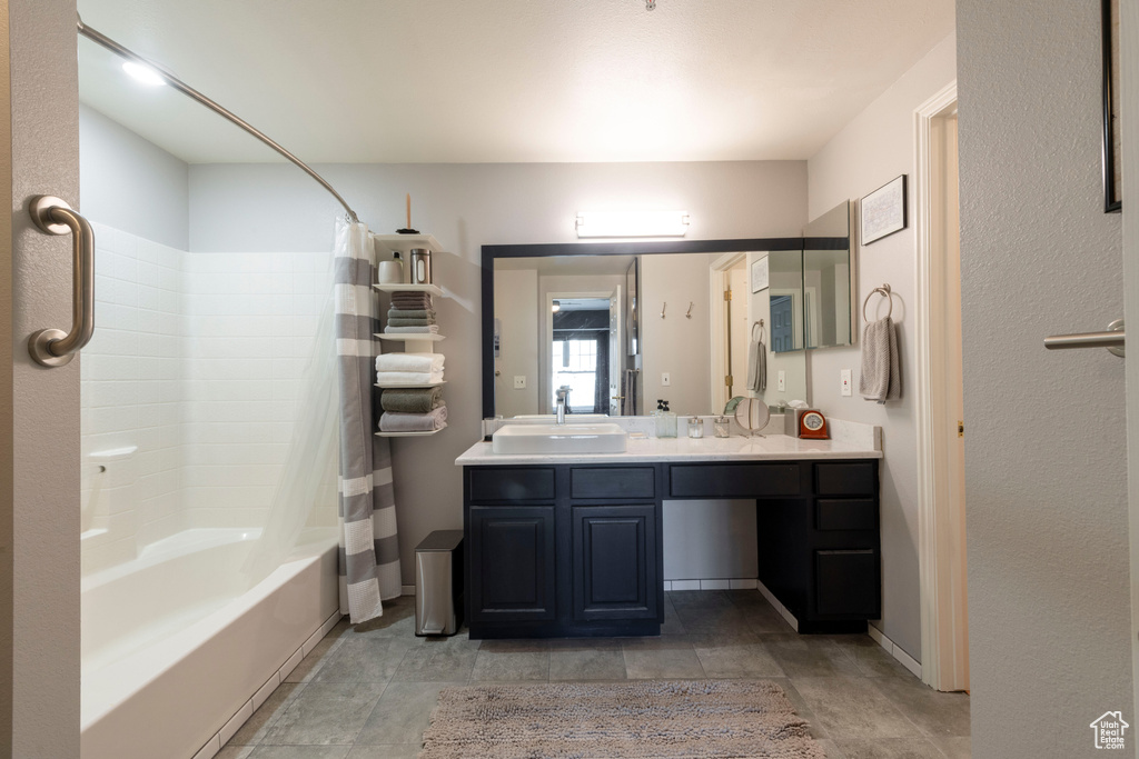 Bathroom featuring shower / tub combo with curtain, double vanity, and baseboards