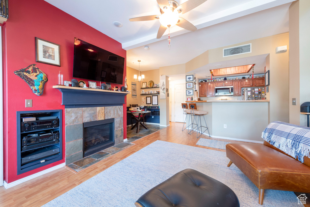 Living area with wood finished floors, ceiling fan, and a tile fireplace