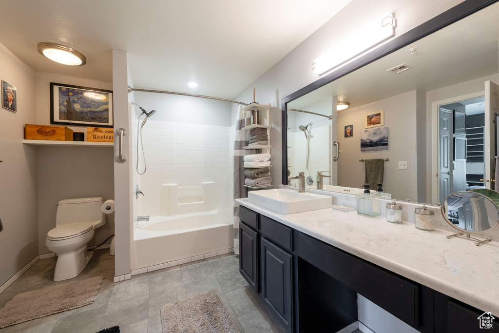 Full bathroom featuring toilet, vanity, bathtub / shower combination, tile patterned floors, and baseboards