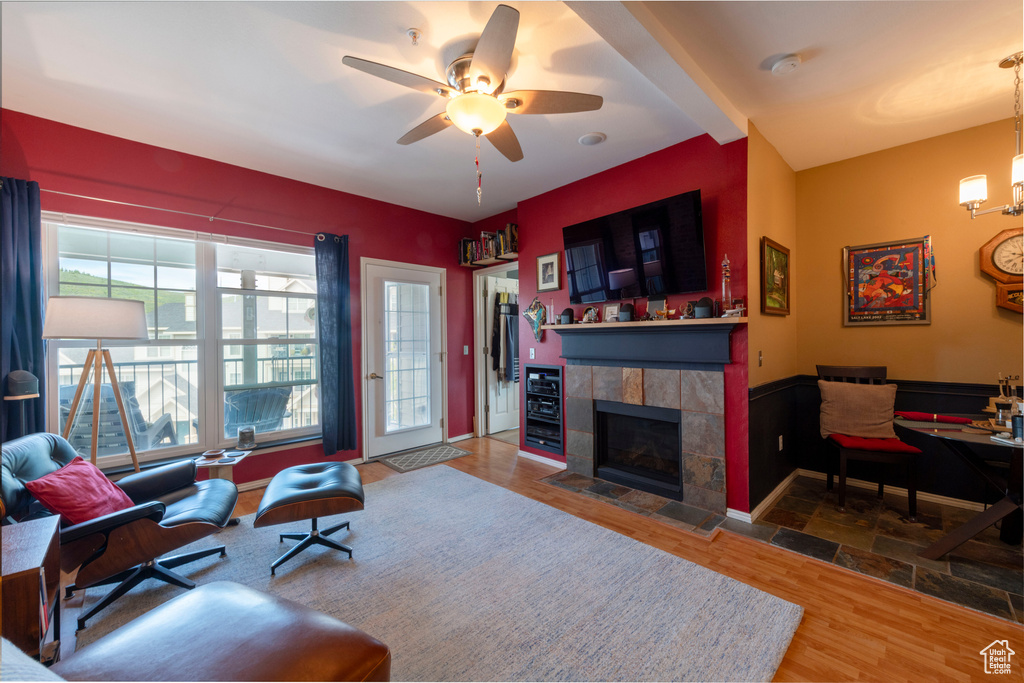Living area with a fireplace, ceiling fan, wood finished floors, and a chandelier