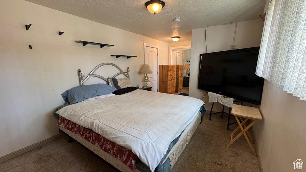Bedroom with a textured ceiling and baseboards