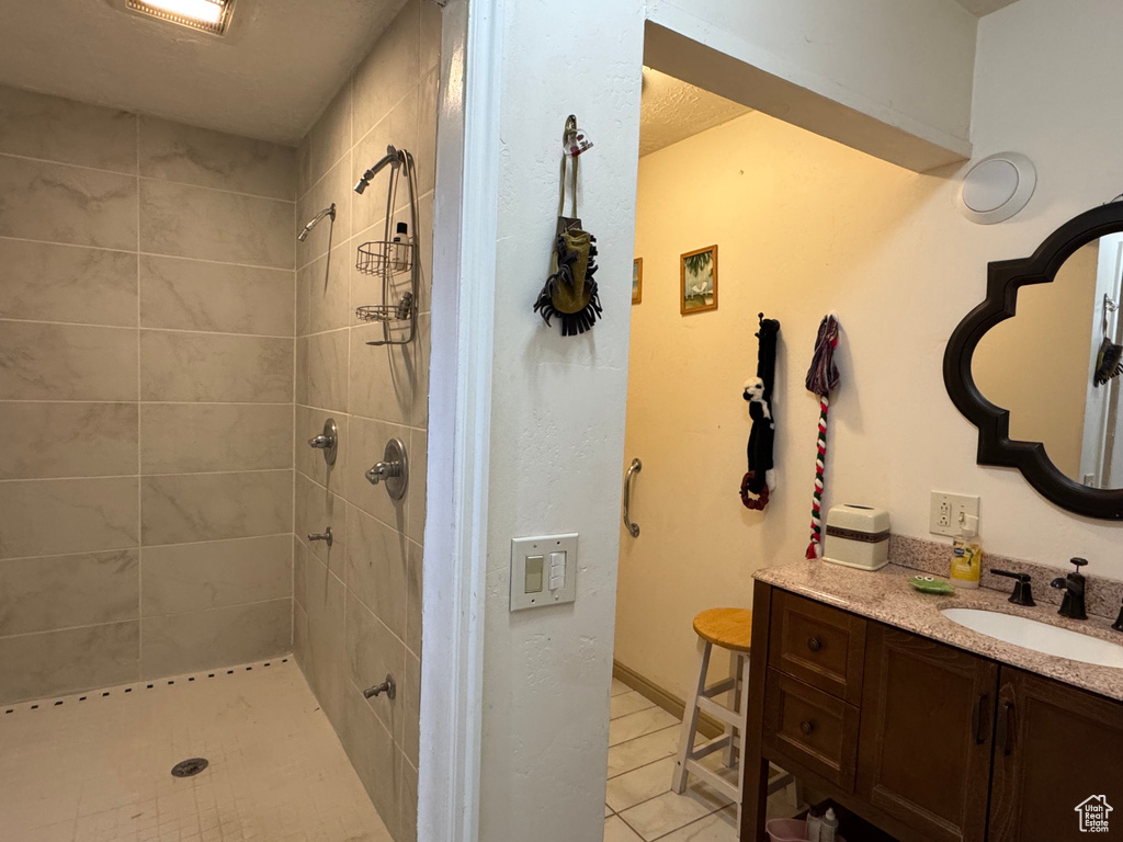 Full bathroom with vanity, tiled shower, and tile patterned floors