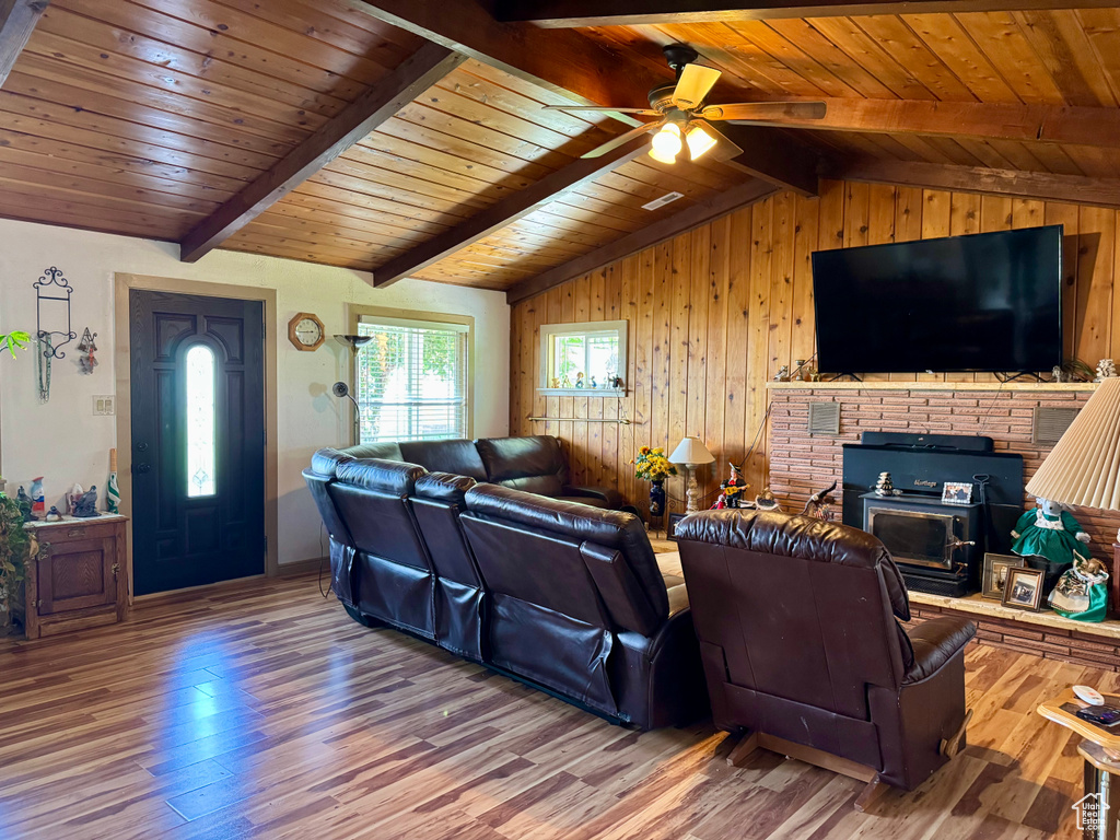 Living room with wood finished floors, ceiling fan, wooden walls, and wood ceiling