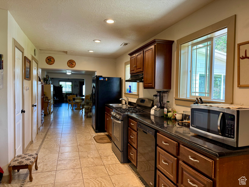 Kitchen with black appliances, under cabinet range hood, a textured ceiling, dark countertops, and recessed lighting