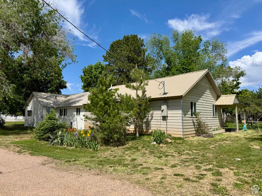 View of front of home featuring metal roof and a front lawn