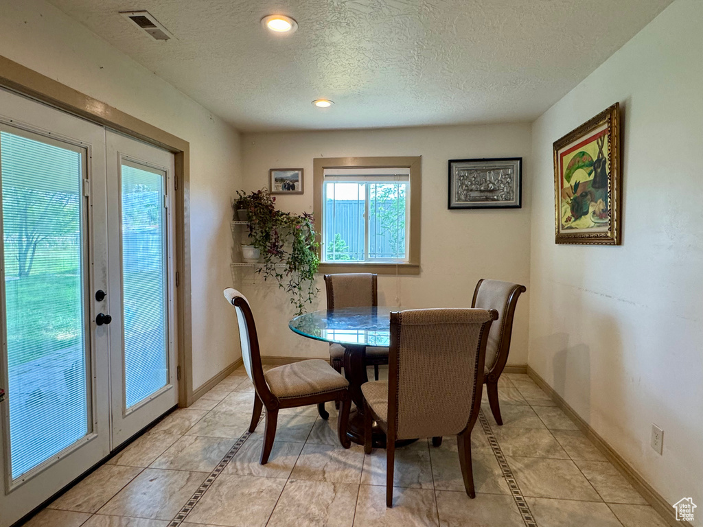 Dining space with a textured ceiling, light tile patterned floors, baseboards, recessed lighting, and french doors