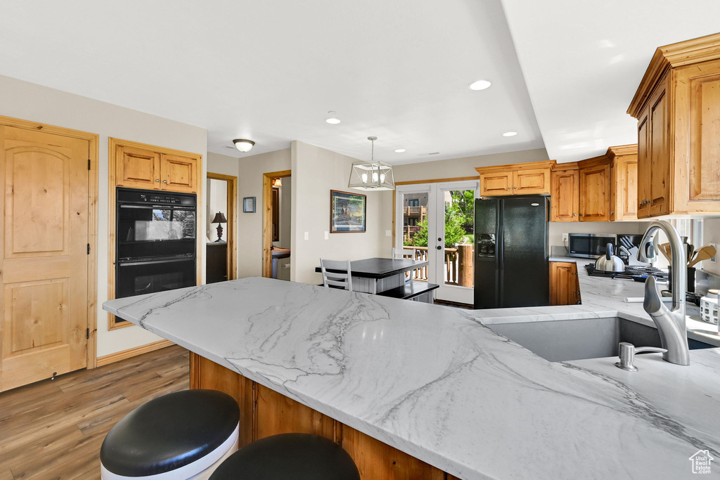 Kitchen with black appliances, a sink, a peninsula, light wood finished floors, and recessed lighting