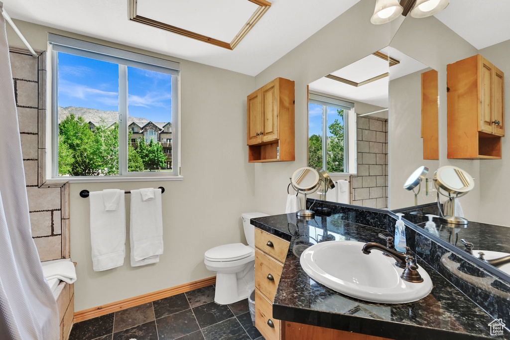 Full bath with baseboards, vanity, toilet, and shower / bathtub combination with curtain
