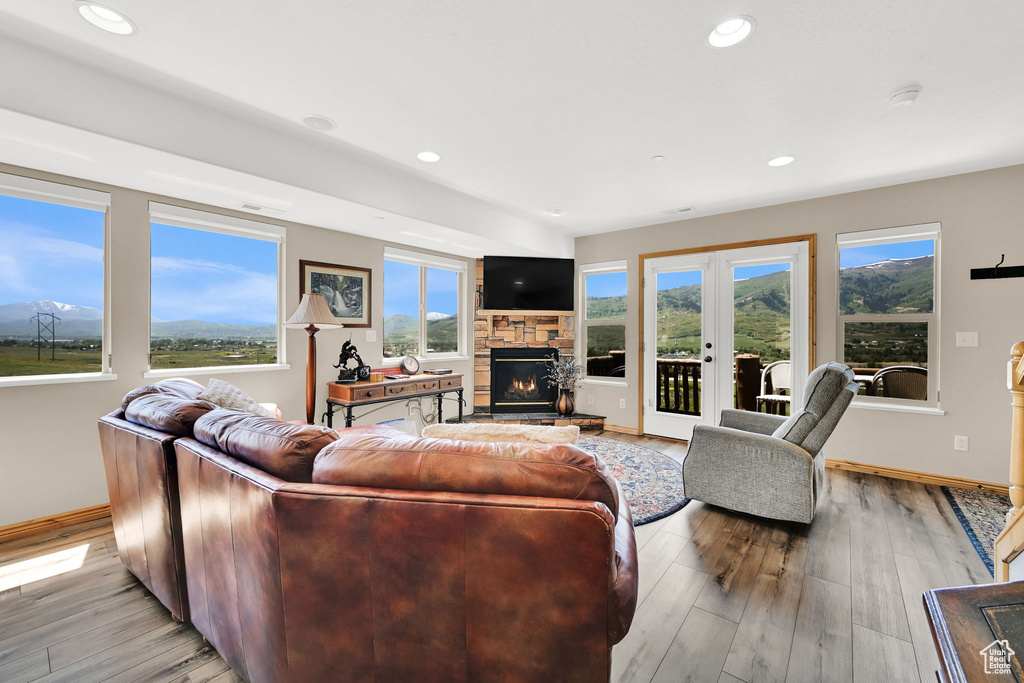 Living area with a fireplace, baseboards, light wood-style floors, recessed lighting, and french doors