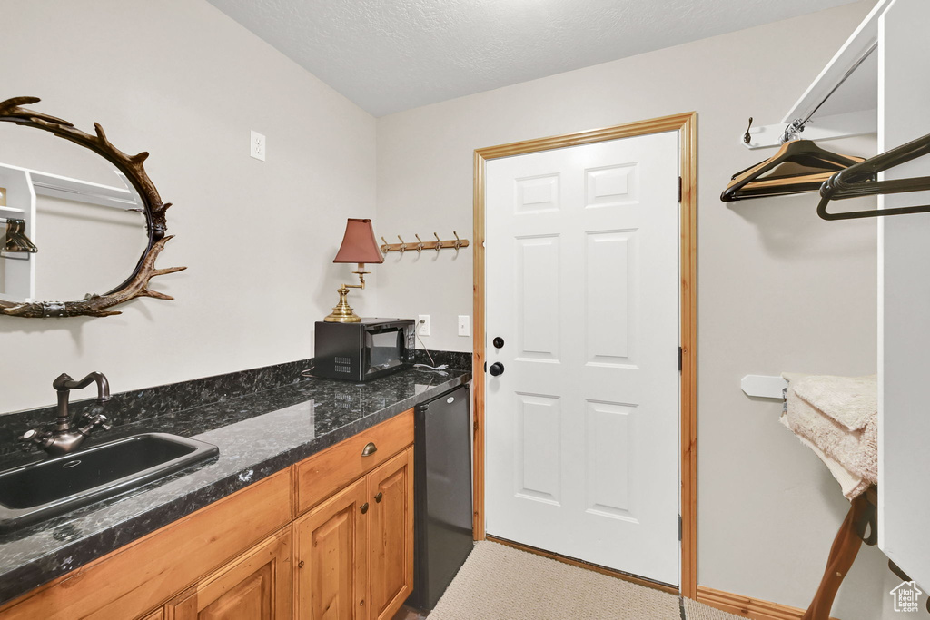 Kitchen with a sink, fridge, and dark stone countertops