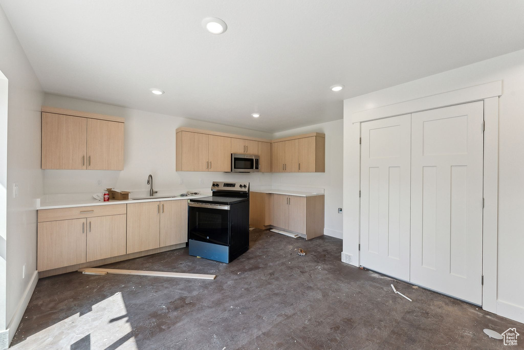 Kitchen with appliances with stainless steel finishes, light brown cabinetry, concrete flooring, a sink, and recessed lighting