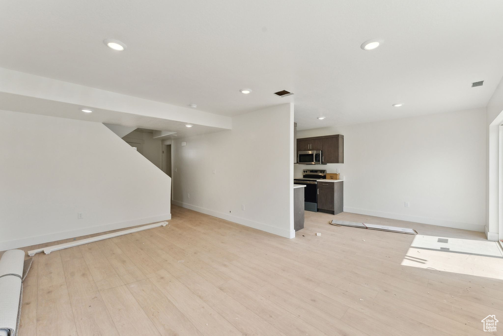 Unfurnished living room featuring recessed lighting, light wood-style floors, and baseboards