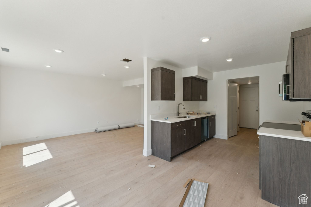 Kitchen featuring a sink, dark brown cabinets, light wood-type flooring, light countertops, and recessed lighting