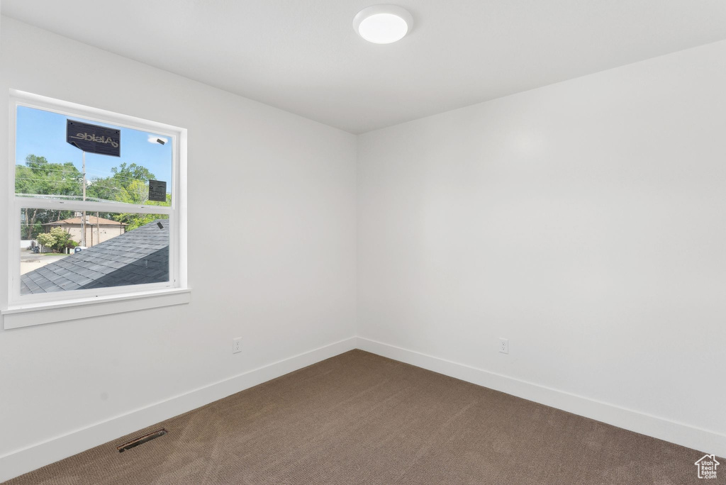 Empty room with dark colored carpet and baseboards