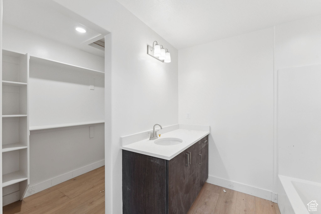 Bathroom featuring wood finished floors, vanity, baseboards, and a bathtub