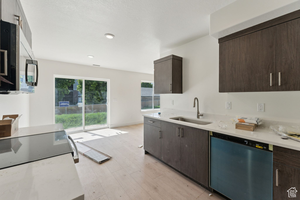 Kitchen featuring dishwasher, a sink, dark brown cabinets, light wood-style floors, and recessed lighting