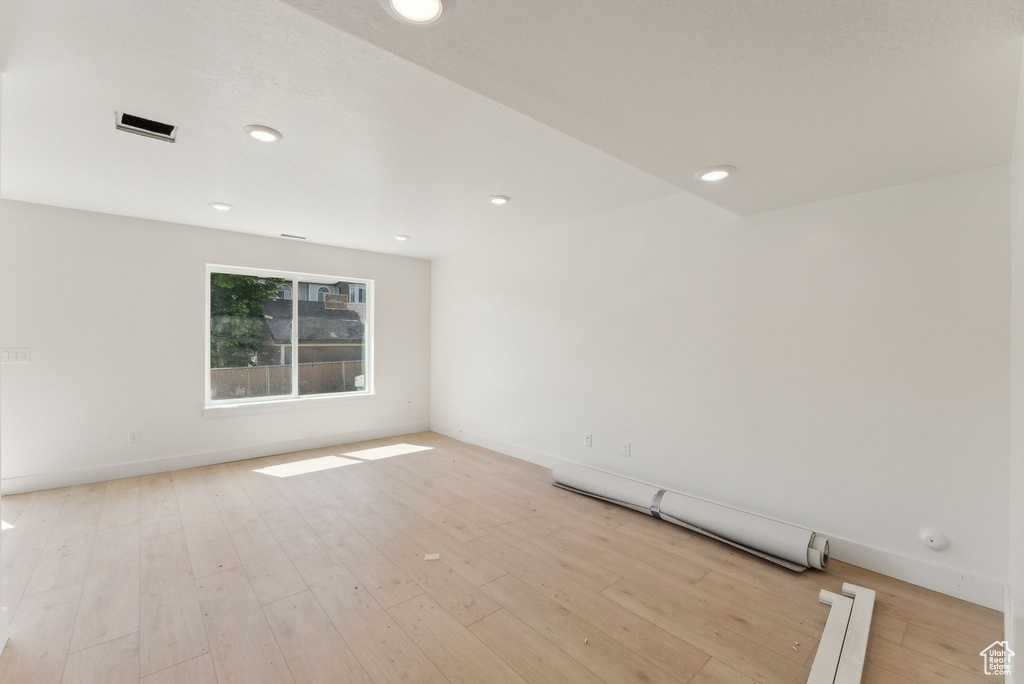 Empty room featuring light wood-style floors, baseboard heating, baseboards, and recessed lighting