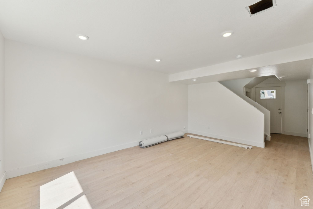 Below grade area with stairs, light wood finished floors, baseboards, and recessed lighting