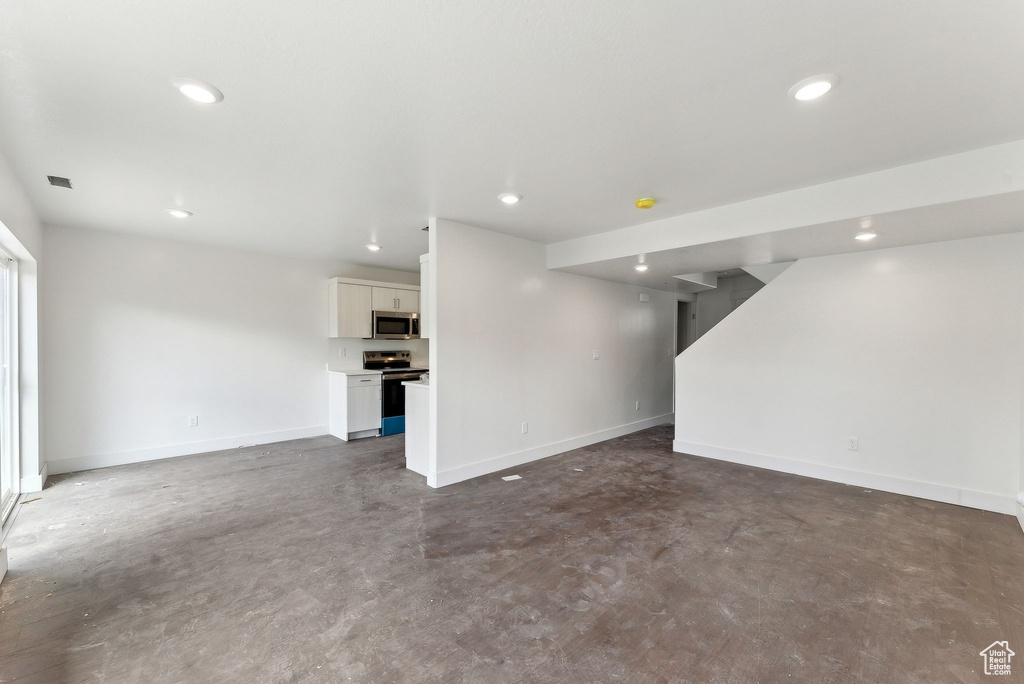 Unfurnished living room featuring concrete floors, recessed lighting, and baseboards