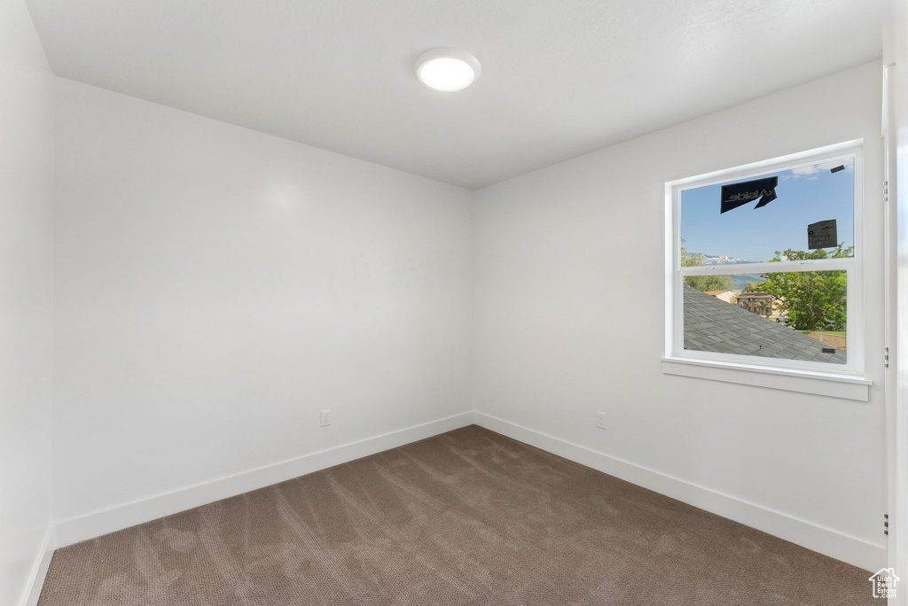 Empty room featuring carpet and baseboards