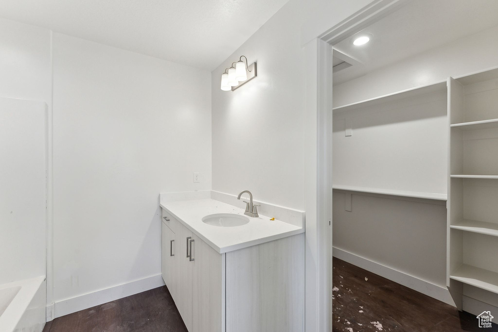 Full bath featuring vanity, wood finished floors, a tub, and baseboards