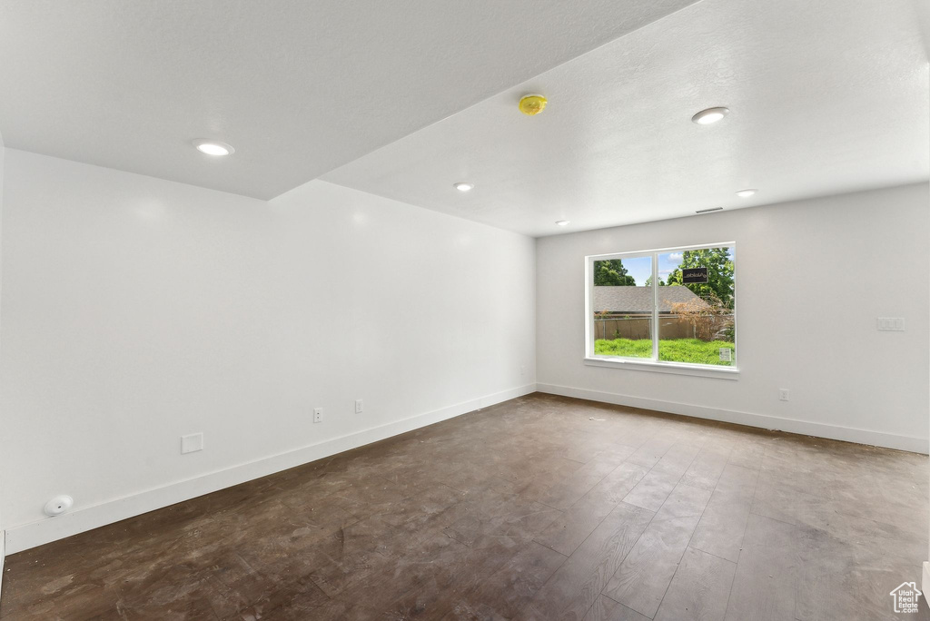 Empty room featuring baseboards, a smoke detector, and recessed lighting