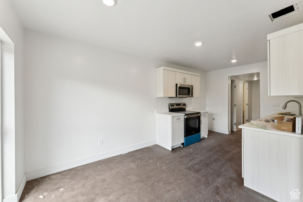 Kitchen featuring stainless steel appliances, a sink, light countertops, baseboards, and recessed lighting