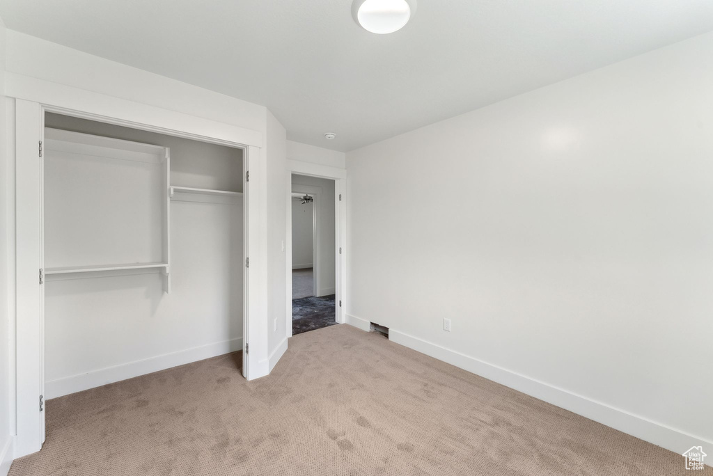 Unfurnished bedroom featuring carpet floors, baseboards, and a closet