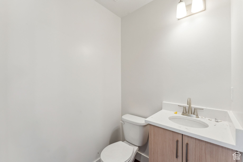 Half bath featuring toilet, vanity, and baseboards