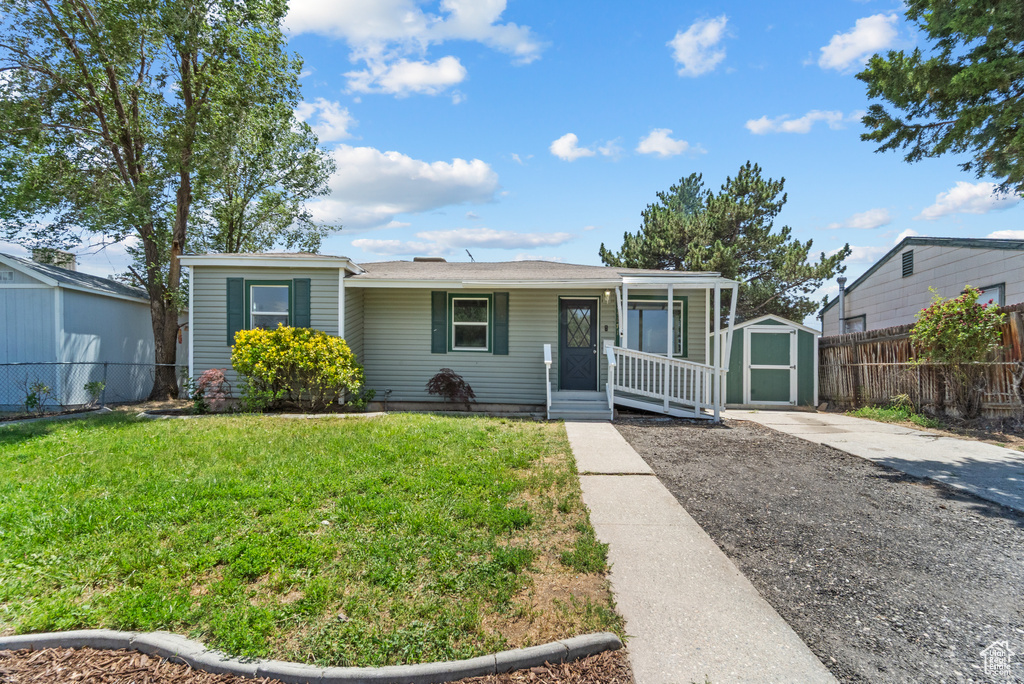 View of front of home featuring a porch and a storage shed