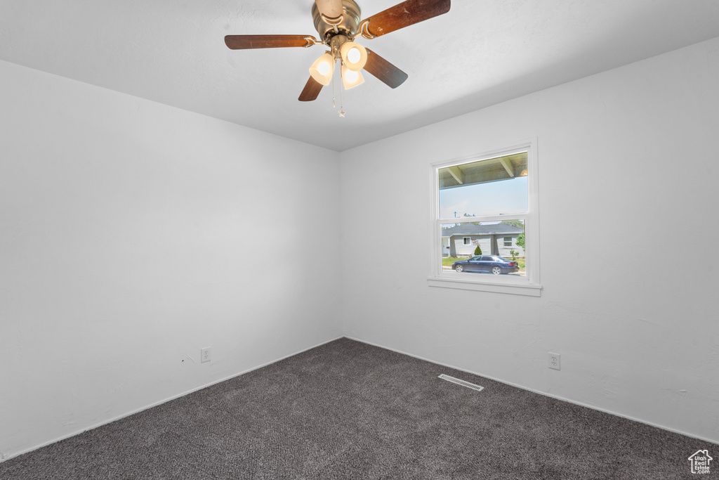 Carpeted spare room featuring a ceiling fan