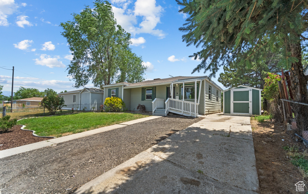 View of front facade featuring a porch, concrete driveway, and a storage unit