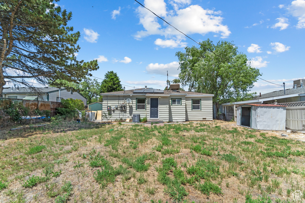 Rear view of house featuring roof mounted solar panels and a storage unit