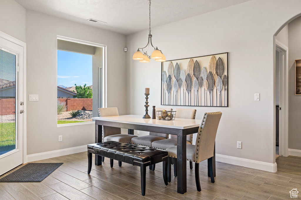 Dining area featuring wood finished floors, arched walkways, a chandelier, and baseboards