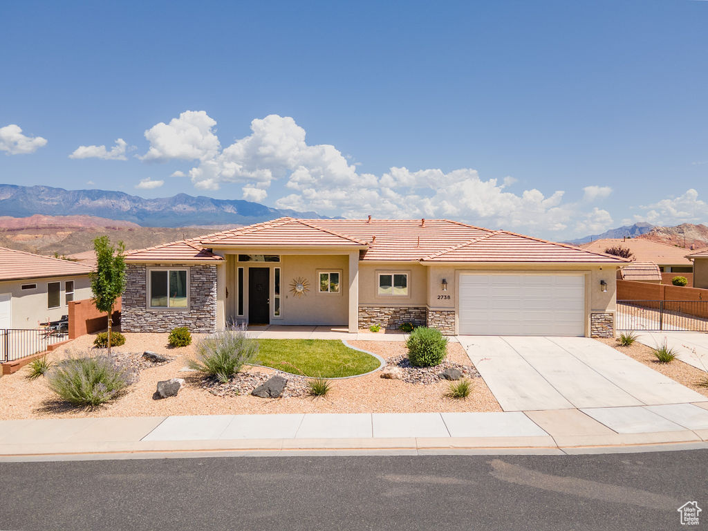 Single story home with stone siding, a mountain view, stucco siding, and a tile roof