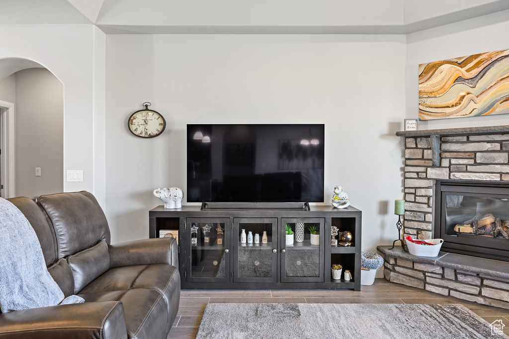 Living area featuring arched walkways, a fireplace, and wood finished floors