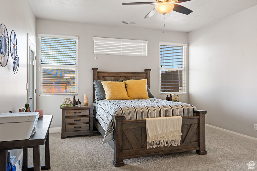 Bedroom featuring light carpet, multiple windows, and baseboards
