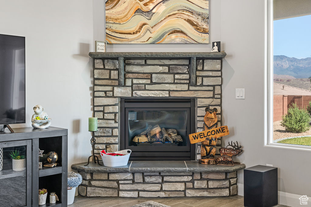 Detailed view of wood finished floors, a fireplace, a mountain backdrop, and baseboards